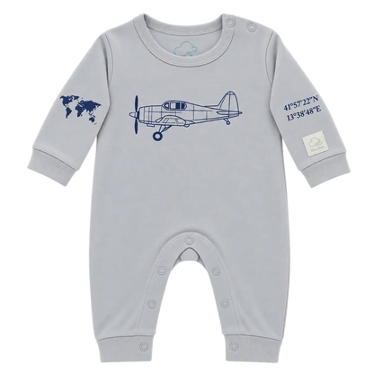 A light gray baby long-sleeve romper with a navy blue airplane graphic on the chest, a world map on one sleeve, and coordinates on the other sleeve, shown on a plain white background.