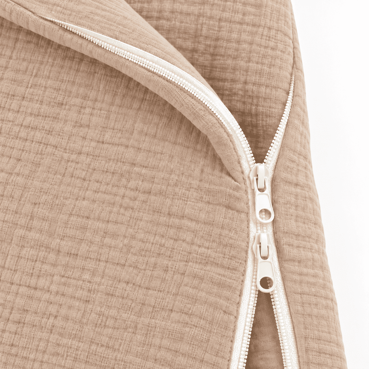 Close-up of a beige textured fabric item with a cream-colored zipper, showing the material detail and pull tab.